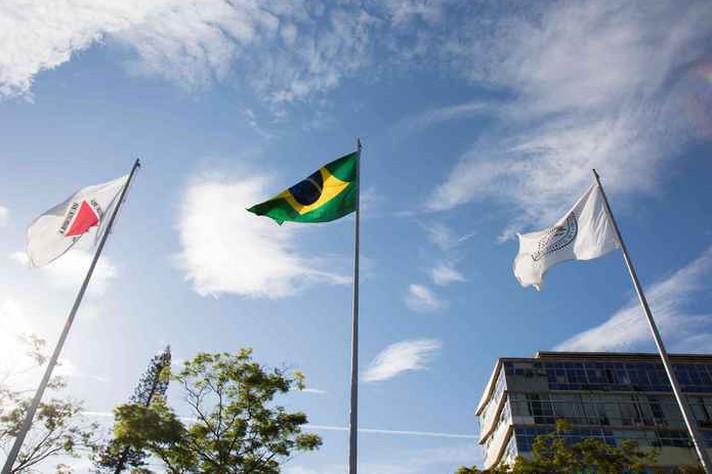 Bandeiras de Minas, do Brasil e da UFMG hasteadas em frente ao prédio da Reitoria