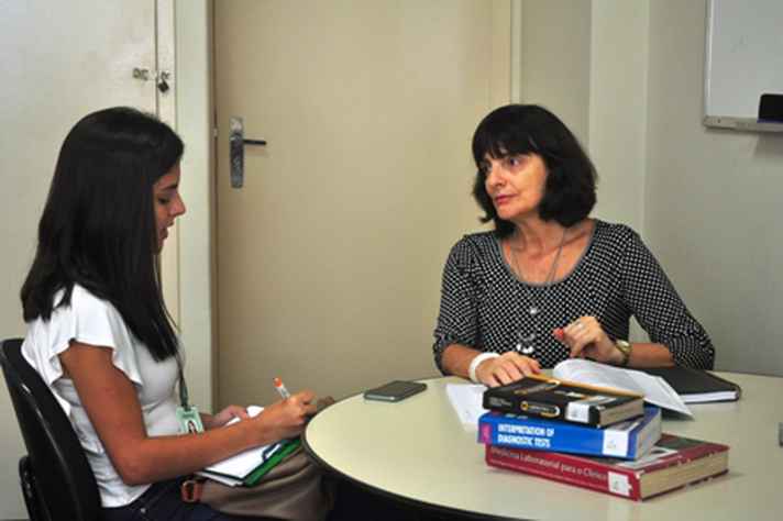 Professora Deborah Carvalho Malta em trabalho de orientação com estudante