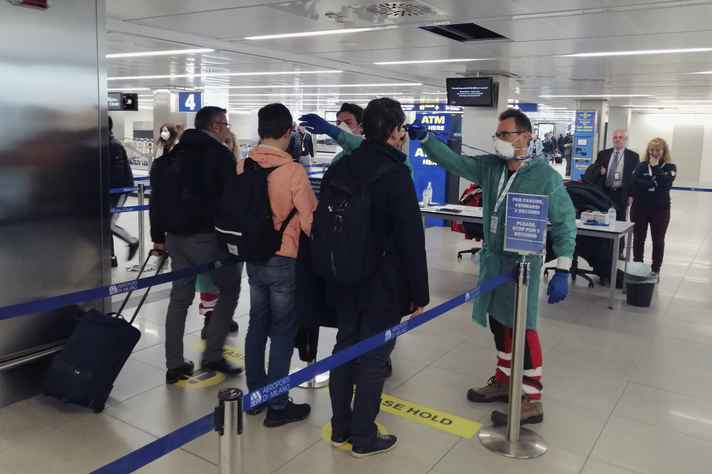Voluntários da proteção civil trabalhando no controle sanitário do aeroporto Linate em Milão, na Itália