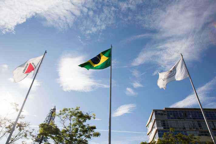 Bandeiras de Minas Gerais, do Brasil e da UFMG hasteadas em frente ao prédio da Reitoria