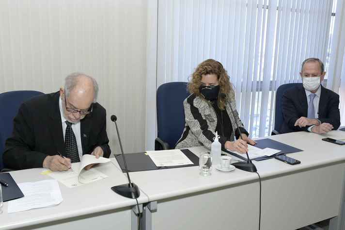 Diretor presidente da Embrapii, Jorge Guimarães assina os termos ao lado da reitora e de Sérgio Freitas, do MCTI